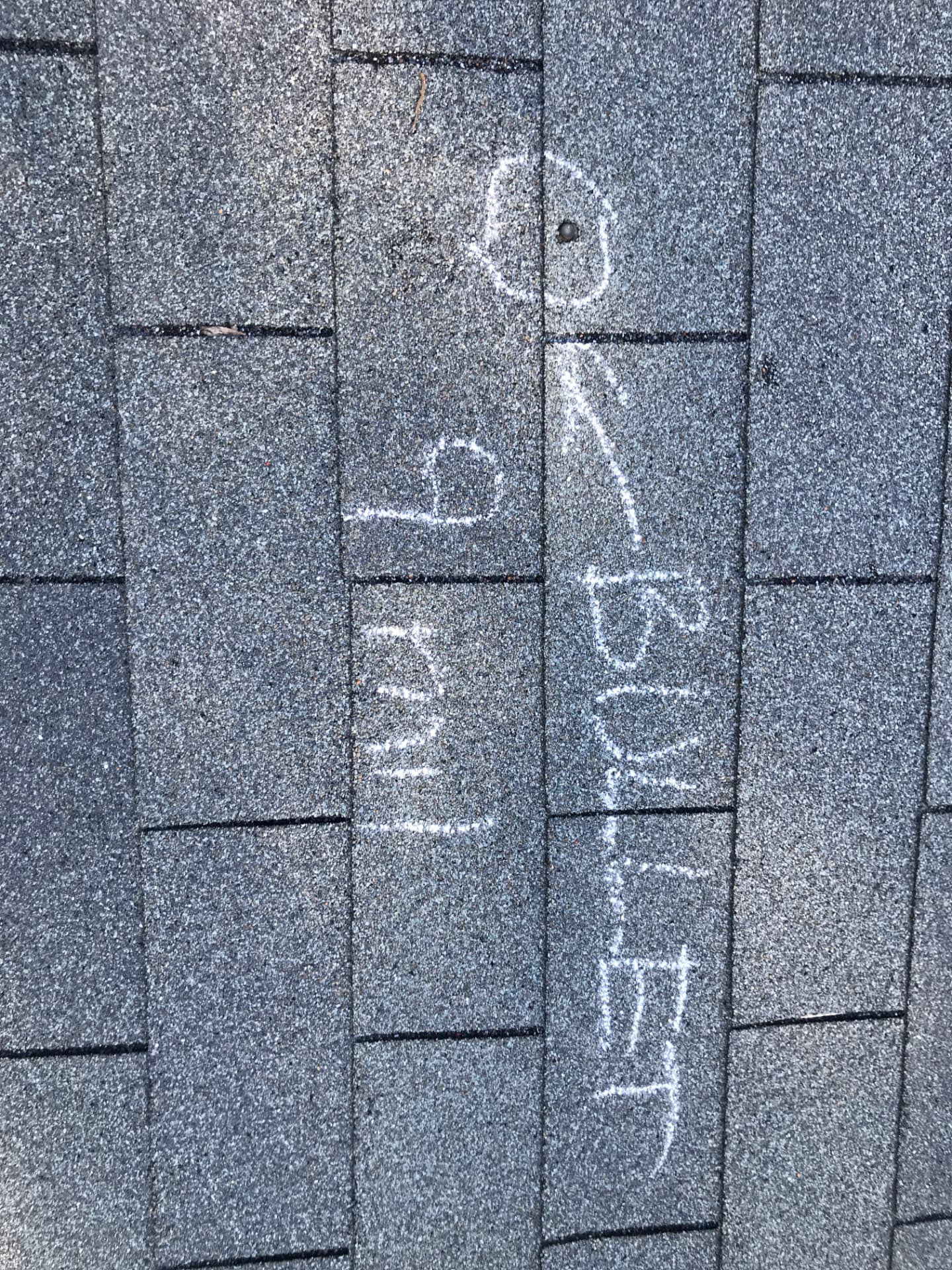 Damage marked in chalk on shingles during a Vest Construction roof inspection